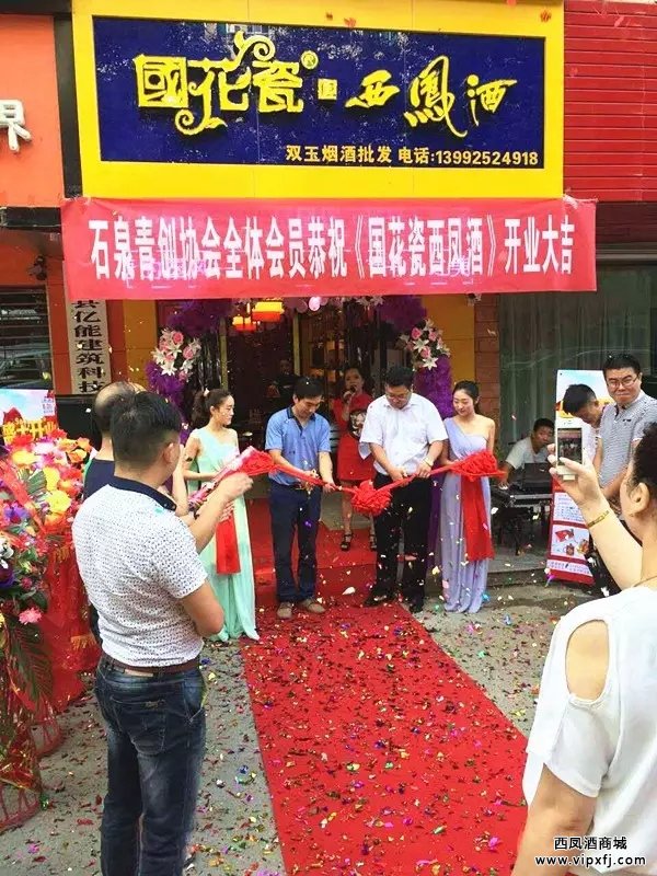 石泉创业协会焦会长与国花瓷西凤酒安康地区区域经理姜亚锋为专卖店开业剪彩